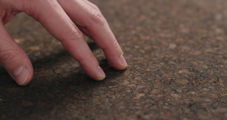 man hand touch dark cork surface with oil finish