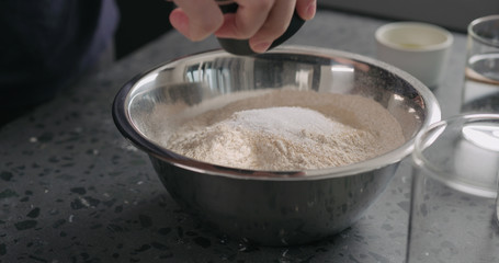 add dry ingredients into flour in steel bowl on concrete countertop