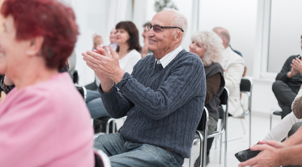 a group of senior citizens applaud in the conference room