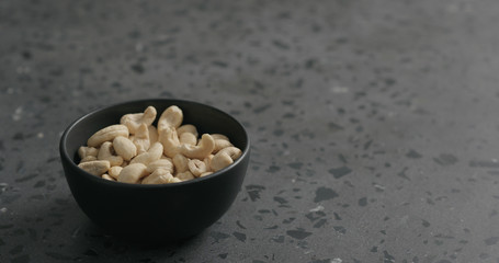 cashew nuts in black bowl on terrazzo countertop