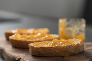 Ciabatta slices with orange marmalade on olive board