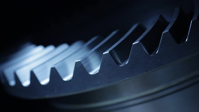 Close-up of a rotating cog wheel in a machinery &ndash; dark blue color