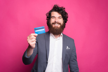 Happy bearded man in suit showing blue credit card.