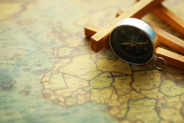 Travel and adventure search concept. Vintage aged map with a shabby book and compass. Shabby book and compass on the table.