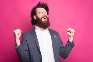 Portrait of amazed bearded man in suit celebrating sucess.
