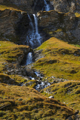Naklejka na ściany i meble A small mountain stream flows down the mountainside.