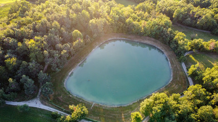 Vista aerea dal drone delle colline italiane sugli Appennini nelle montagne di Modena, Italia, con un laghetto, boschi, stradine, campi e prati