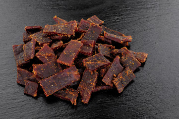 Beef jerky meat slices on a slate stone background
