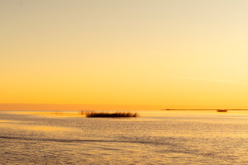 Sunset sky background. Gold sunset sky with evening sky clouds over the lake with fog.Crystal clear water texture. Small waves with water reflection