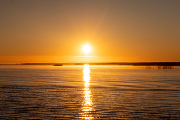 Sunset sky background. Gold sunset sky with evening sky clouds over the lake with fog.Crystal clear water texture. Small waves with water reflection