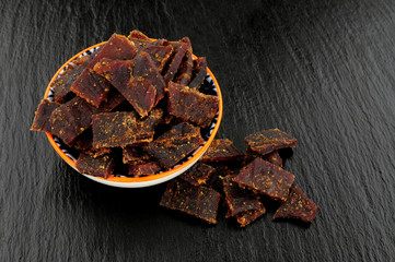 Beef jerky meat slices on a slate stone background