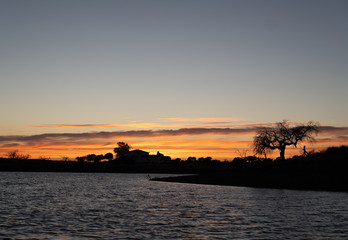 Puesta de sol con cortijo y encinas al fondo junto al Pantano de Villalba de los Barros