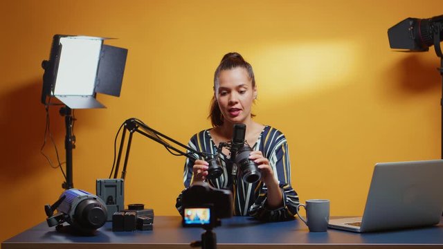 Content creator making a camera lens comparison in her professional studio set. Content creator new media star influencer on social media talking video photo equipment for online internet web show