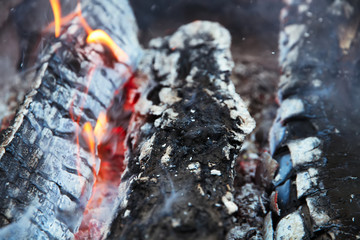 Glowing embers in hot red color, abstract background. The hot embers of burning wood log fire. Firewood burning on grill. Texture fire bonfire embers.