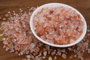 Himalayan pink salt in bowl and on wooden table	