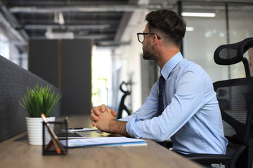 Fototapeta premium Focused businessman thinking at modern office into report file calculating stock market earnings, startup business.