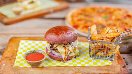 Closeup shot of a delicious cheeseburger with french fries on the table