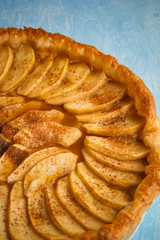 Homemade organic pie with apples puff pastry, cinnamon and butter. Delicious apple puff with blue background.