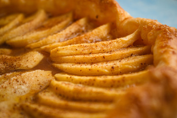 Homemade organic pie with apples puff pastry, cinnamon and butter. Delicious apple puff with blue background.