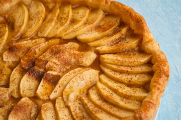 Homemade organic pie with apples puff pastry, cinnamon and butter. Delicious apple puff with blue background.