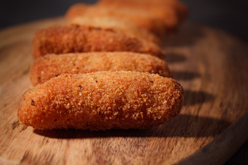 Homemade traditional spanish croquettes on a wood board and black background. Tapas food. Dark food.