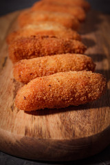 Homemade traditional spanish croquettes on a wood board and black background. Tapas food. Dark food.