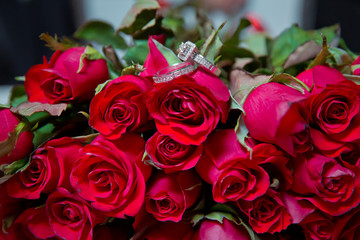 Rings on the wedding bouquet . Gold wedding rings on a bouquet of red gold flowers.