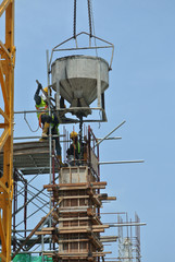 JOHOR, MALAYSIA -MAY 06, 2016: A group of construction workers pouring concrete using concrete bucket into the column formwork at the construction site.  