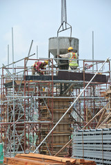 JOHOR, MALAYSIA -MAY 06, 2016: A group of construction workers pouring concrete using concrete bucket into the column formwork at the construction site.  