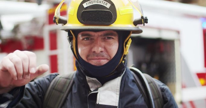 Close up portrait of fireman in helmet and gull equipment standing next to the car. Rescuer opening helmet and smiling looking at camera. Concept of saving lives, heroic profession, fire safety