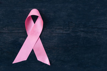 Pink ribbons on wood background.
