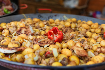 Delicious baked potatoes in iron pan with onion and bell pepper on fairs in Budapest