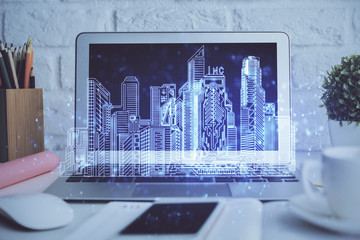 Desktop computer background in office and big town buildings hologram drawing. Double exposure. Smart city concept.