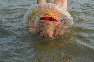 A child with a circle dives headfirst into the water.