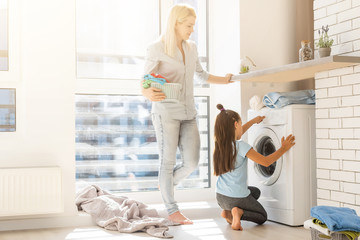 Fototapeta premium family mother and child girl little helper in laundry room near washing machine and dirty clothes