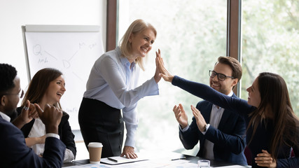 Aged female business trainer or coach giving high five to trainee for correct answer, old lady team...