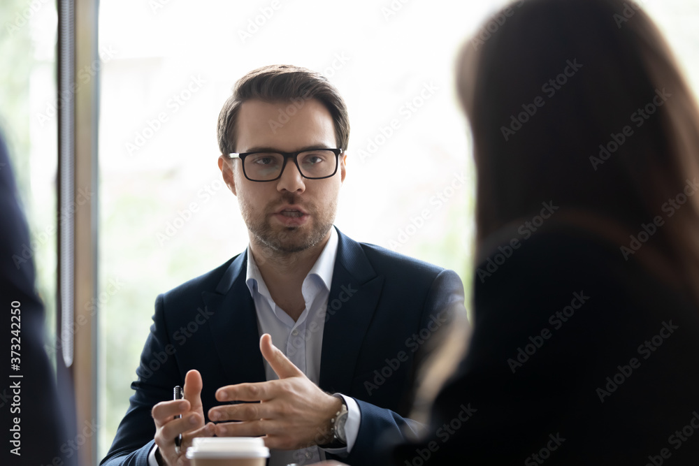 Wall mural Contributing ideas. Confident office worker explaining project details to his colleagues on briefing, businessman sharing plans with partners, young manager presenting his concept on corporate meeting