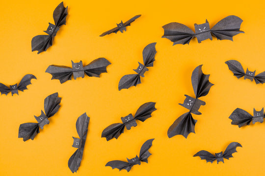 Many bats made of paper on an orange background. Flat lay. The concept of Halloween, and holiday decorations