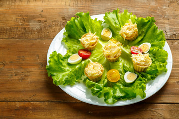 Tartlets with cheese and garlic on a plate with salad on a wooden table.