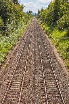 Zwei parallel verlaufende Bahngleise an einem sonnigen Tag.