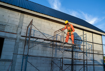 Roofer worker in protective uniform wear and safety line working install new roof at construction site.
