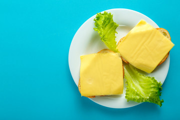 Sandwiches with cheese and cherry on a plate on a blue background. Copy place.