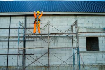 Obraz premium Roofer worker in protective uniform wear and safety line working install new roof at construction site.