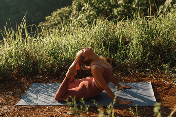 Young woman in sports wear  exercising in park, practise yoga asana in summer park, stretching