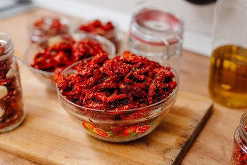 Sun-dried tomatoes. The process of cooking sun-dried tomatoes. The woman is preparing tomatoes in the kitchen. A woman cuts tomatoes, greases them with oil and spices them. 