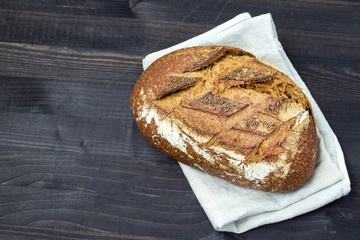 Rye bread on a dark wooden background. Fresh bread. Close-up. A loaf of bread. Top view. Copy space for text.