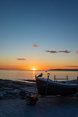 Sandy beach during sunrise with fishing boat and seagull in the foreground