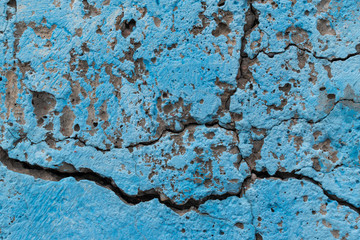 Concrete wall for the backdrop. Large cracks in the wall surface. Blue paint.