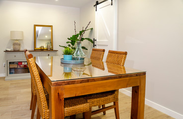 Bright dining room with a wooden table and rattan chairs.
