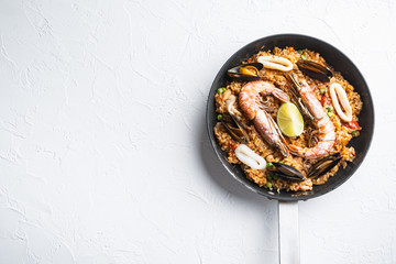 Paella with seafood and chicken on white background, top view with space for text